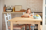 Young Girl At Home Using Digital Tablet On Kitchen Table