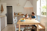 Children At Home Using Digital Devices On Kitchen Table