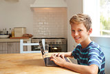 Portrait Of Boy At Home Using Laptop On Kitchen Table