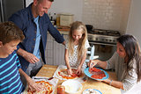 Family At Home In Kitchen Making Pizzas Together