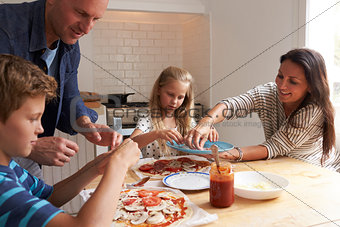 Family At Home In Kitchen Making Pizzas Together