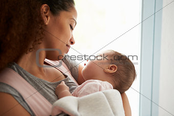 Close Up Of Mother Cuddling Baby Daughter At Home