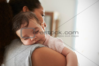 Close Up Of Mother Cuddling Sleeping Baby Daughter At Home