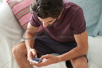Man Sitting On Sofa Using Mobile Phone To Text Message
