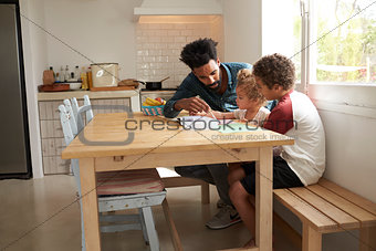 Children And Father Painting Picture On Kitchen Table