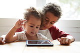 Children At Home Using Digital Tablet On Kitchen Table
