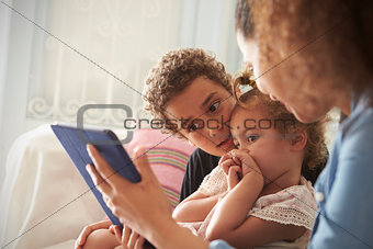 Mother And Children Sitting On Sofa Using Digital Tablet