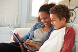 Mother And Son Sitting On Sofa Using Digital Tablet