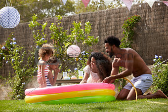 Family Having Fun In Garden Paddling Pool