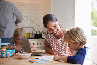 Kids doing homework at kitchen table with mum, close up