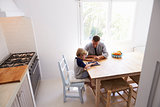 Dad and son use tablet in kitchen, elevated view from doorway