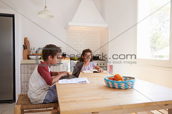 Brother and sister doing homework at kitchen table