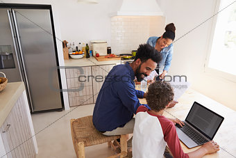 Parents helping kids with homework in kitchen, elevated view