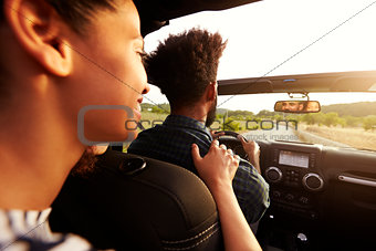 Excited woman in the back of car, hand on shoulder of driver