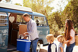 Family packing up their camper van for a road trip vacation