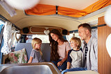 Family sitting inside a camper van looking at each other