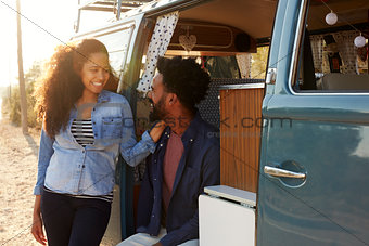 Couple making a roadside stop in their van look at each other