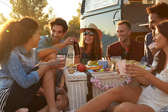 Friends enjoying a picnic beside their camper van