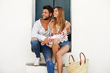 Happy couple sitting in a doorway looking away, Ibiza, Spain
