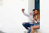 Happy couple sitting on stairs taking a selfie, Ibiza, Spain