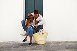 Adult couple sitting on steps looking at a guidebook, Ibiza