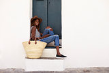 Young woman on holiday sitting on steps, looking to camera