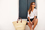 Young woman wearing sunglasses sitting on steps looking away