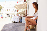 Young woman sitting on steps looking at her phone, side view