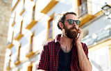 Bearded young man in sunglasses using phone, Ibiza, Spain