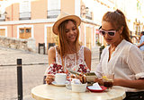 Two female friends reading a guidebook outside a cafe, Ibiza