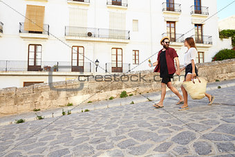 Couple on holiday walking with guidebook, holding hands