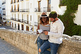 Couple leaning against a wall reading a guidebook, Ibiza