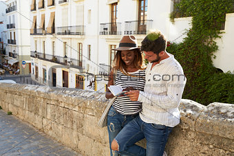 Couple leaning against a wall reading a guidebook, Ibiza