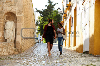 Couple on holiday walking in Ibiza streets talking
