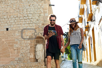 Couple on holiday walk, reading a guidebook, three quarters