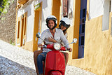 Couple riding motor scooter in old Ibiza street, close up