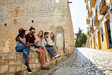 Five friends on holiday sitting on a wall in Ibiza