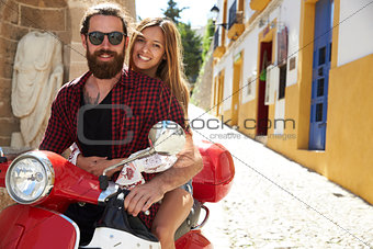 Couple sitting on motor scooter, looking to camera, Ibiza