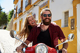 Couple sitting on a motor scooter laughing, Ibiza, Spain