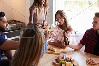 Five friends making a toast in the kitchen at a dinner party