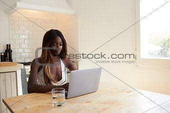 Young woman using laptop computer in her kitchen, close up