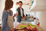 Young adult couple  preparing food, looking at each other
