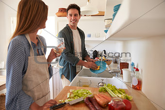 Young adult couple  preparing food, looking at each other