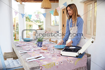 Young woman preparing table on a terrace for a dinner party