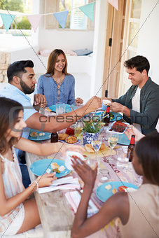 Friends serving each other at a dinner party on a patio
