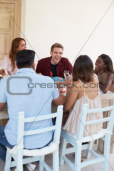 Friends sitting at a dinner party on a patio, vertical