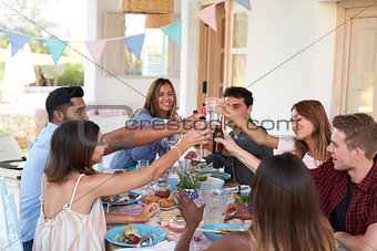 Friends making a toast at a dinner party on a patio, Ibiza