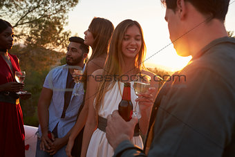 Adult friends at a party on a rooftop at sunset, close up