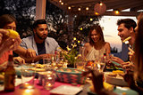 Friends eat and talk at a dinner party on a patio, close up