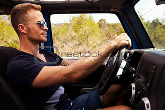 Side View Of Man Driving Open Top Car On Country Road